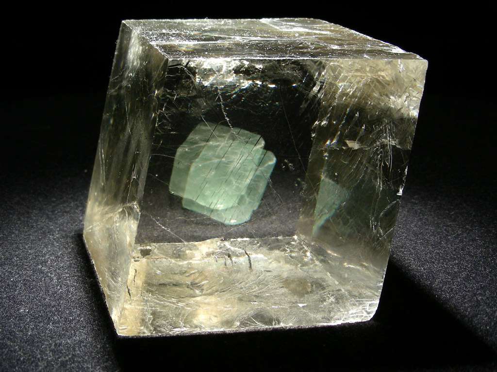 Avec l'octaèdre de fluorine verte placé derrière, on voit bien la biréfringence de la calcite optique ou spath d'Islande. © www.carionmineraux.com