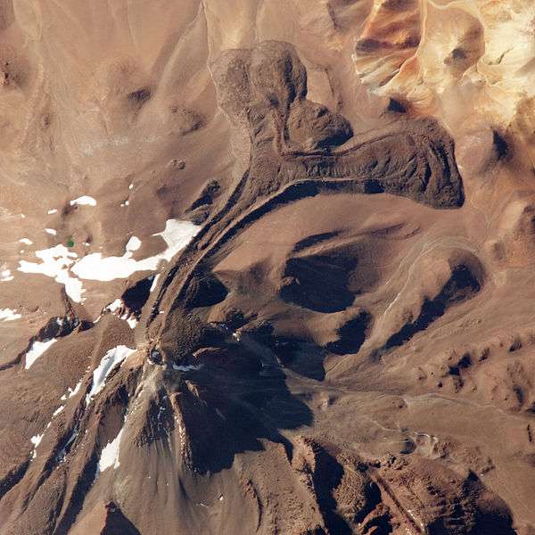 Le Llullaillaco, le plus haut volcan actif au monde, vu de l'espace. Il est recouvert par plusieurs glaciers, mais le site de prélèvement n'a pas été enfoui sous la glace depuis 48.000 ans. Une coulée de lave est clairement visible dans la moitié supérieure droite de la photographie. © Nasa