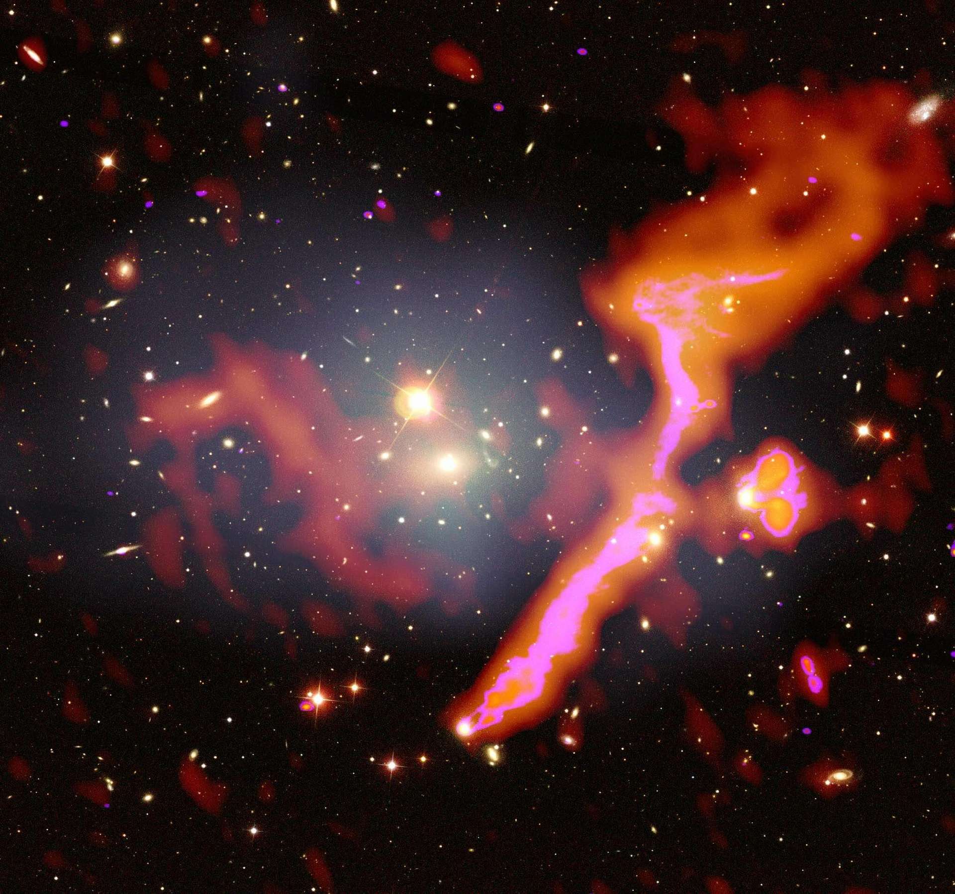L'amas de galaxies Abell 1314, à 460 millions d'années-lumière de nous, vu dans le domaine des ondes radio par LOFAR (en rouge et rose), superposé à son image en lumière visible. Les émissions radio proviennent de sa fusion avec un autre amas. © Amanda Wilber/LOFAR Surveys Team/Nasa/CXC