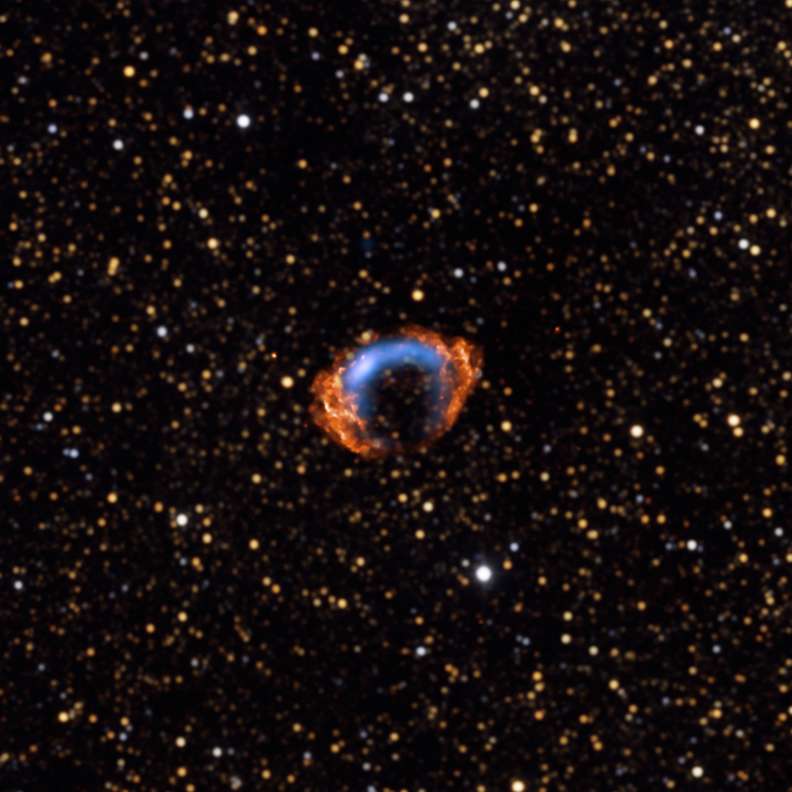 G1.9+0.3, les étoiles en jaune et blanc émettent en infrarouge. En bleu, l'image radio et en orange l'image en X. Crédit : X-ray (Nasa/CXC/NCSU/S.Reynolds et al.); Radio (NSF/NRAO/VLA/Cambridge/D.Green et al.