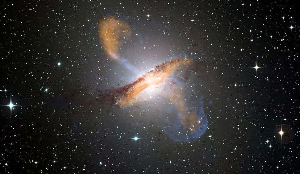 Une image de Centaurus A, révélant les jets émis par le très actif trou noir central de la galaxie. Ceci est une image composite obtenue avec trois différents instruments, fonctionnant à différentes longueurs d'onde. Les données submillimétriques à 870 microns de l’instrument Laboc sur Apex sont montrées en orange. Les données aux rayons X de Chandra sont montrées en bleu. Les données de lumière visible du Wide Field Imager (WFI) du télescope MPG-Eso de 2,2 mètres situé à La Silla, au Chili, montrent les étoiles et la ligne de poussières caractéristique de la galaxie quasiment en couleurs « réelles ». © Eso, Nasa