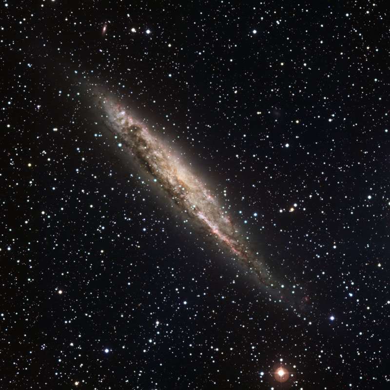 NGC 4945 vue par la tranche. Les observations laissent supposer que ce foisonnement d’étoiles est une galaxie spirale qui ressemble à notre Voie lactée, avec des bras lumineux en spirales et une barre centrale. Les zones brillantes roses révèlent les régions d’intense formation stellaire connues sous le nom de région HII. Toutefois, au-delà de ces ressemblances, le centre de NGC 4945 est beaucoup plus lumineux et accueille très certainement un trou noir super-massif qui dévore d’énormes quantités de matière et éjecte de l’énergie dans l’espace. NGC 4945 se situe à seulement 13 millions d’années-lumière, dans la constellation du Centaure. Elle apparaît magnifiquement dans cette image prise en utilisant 5 filtres (B, V, R, H-alpha et SII) avec le télescope de 2,20 mètres MGP/ESO à La Silla. Le champ est de 30 x 30 arcminutes (le nord en haut et l’est à gauche). © ESO