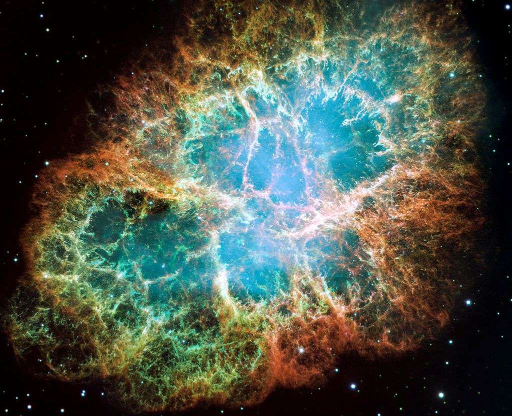 Observée ici par Hubble, la nébuleuse du Crabe est le reste de l’explosion d’une étoile située à environ 6.300 années-lumière de la Terre. La supernova était visible sur Terre en 1054. Le reste de l’étoile qui se trouve vers le centre de la nébuleuse est un pulsar. PSR B0531+21 tourne sur lui-même environ 30 fois par seconde. L'image est formée de l'assemblage de 24 prises individuelles de la Wide Field and Planetary Camera de Hubble. Les couleurs trahissent l’existence de différents éléments expulsés lors de l'explosion. Le bleu représente l'oxygène neutre, le vert le soufre ionisé une fois et le rouge indique l'oxygène ionisé deux fois. © Nasa, Esa, J. Hester, A. Loll (université de l’État d’Arizona)