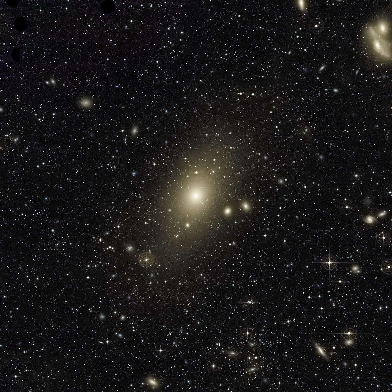 La galaxie elliptique géante Messier 87 et le vaste halo qui l’entoure. Un excès de lumière dans l’angle supérieur droit de ce dernier ainsi que le mouvement qui anime les nébuleuses planétaires en son sein constituent les derniers signes apparents d’une collision récente entre une galaxie de taille moyenne et M87. De nombreuses autres galaxies sont visibles sur cette image. Toutes appartiennent à l’amas de la Vierge que domine Messier 87. Les deux galaxies situées dans l’angle supérieur droit sont surnommées « Les Yeux ». © Chris Mihos (Case Western Reserve University), Eso
