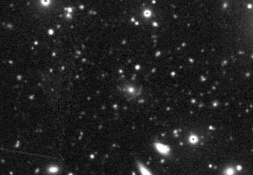 Image de la zone par le télescope Magellan de 6,5 mètres au Chili. L’énorme force de gravitation de l’amas récemment découvert forme un mirage cosmique, visible sous la forme d’un arc au centre de l’image. Crédits : Werner et al. 2007