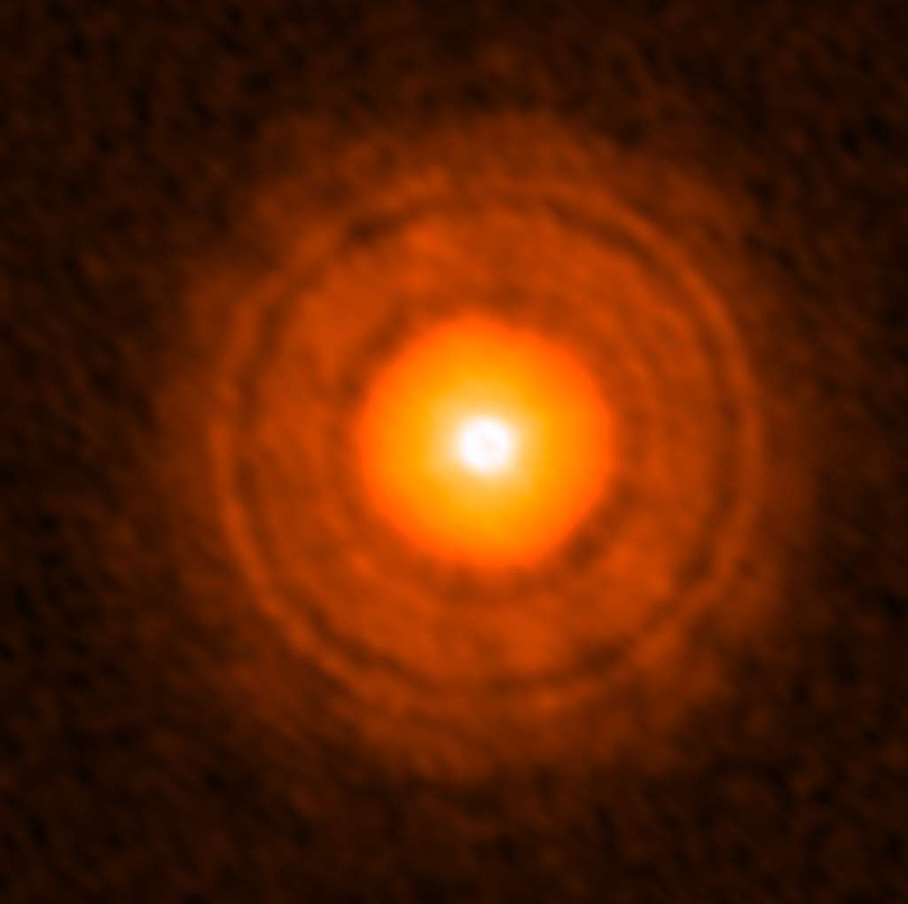 Sur cette image en fausses couleurs prise par Alma, le disque protoplanétaire autour de l'étoile TW Hydrae est bien visible ainsi que des anneaux moins lumineux. Il s'agit de régions moins denses en gaz et poussières, dépourvues de particules de grandes tailles et qui seraient la manifestation de la présence d'exoplanètes. © Alma (ESO/NAOJ/NRAO), Tsukagoshi et al.