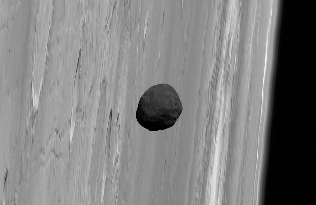 Phobos, un sombre satellite qui passe devant Mars. Il ressemble aux météorites à chondrites carbonées qui proviennent des régions les plus éloignées de la ceinture d’astéroïdes. Ce qui laisse à penser qu’il ne s’est pas formé en même temps que Mars ni à partir des mêmes matériaux. © G. Neukum (FU Berlin) et al., Mars Express, DLR, ESA