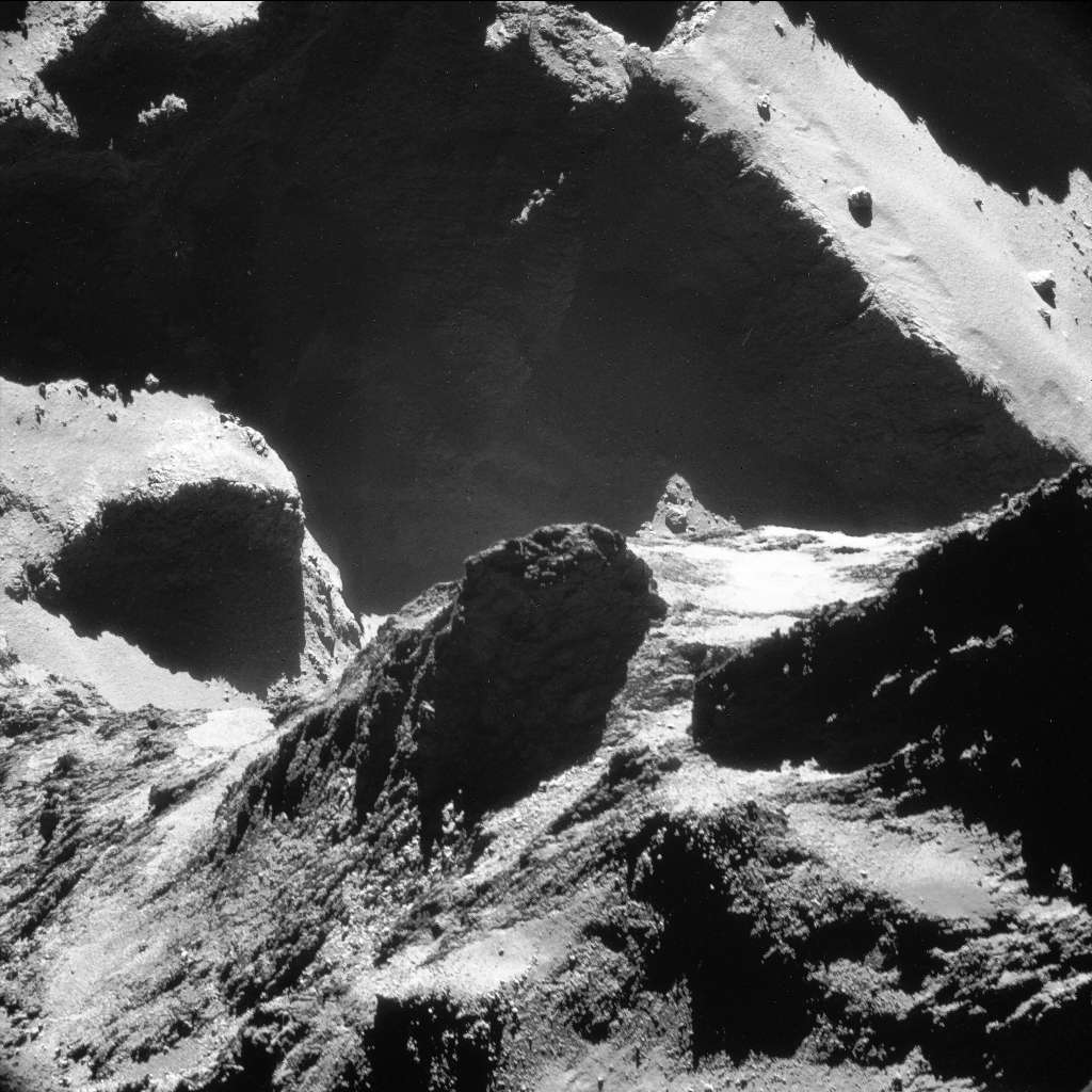 Paysages variés à la surface de la comète 67P/Churyumov-Gerasimenko, photographiée ici par Rosetta le 19 octobre 2014 à seulement 9,9 km du centre du noyau. Les reliefs au premier plan appartiennent au petit lobe où s’est posé Philae le 12 novembre. Une partie du plus grand lobe est visible à l’arrière-plan. Entre les deux, dans l’ombre, au pied des parois sombres, il y a le « cou » de la comète, un des sites les plus actifs. La résolution de l’image est de 77 cm par pixel. © Esa, Rosetta, NavCam – CC BY-SA IGO 3.0