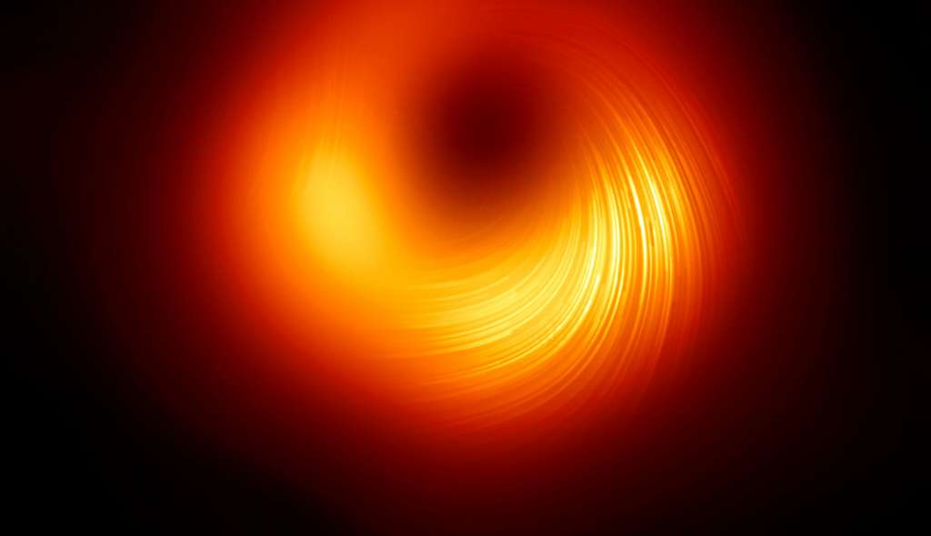 Cette image offre une vue polarisée du trou noir de M87*. Les lignes indiquent l’orientation de la polarisation, étroitement liée au champ magnétique qui entoure l’horizon du trou noir. © EHT Collaboration
