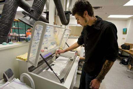 Grant Marchelli prépare son imprimante 3D en étalant une fine poudre de verre. © University of Washington