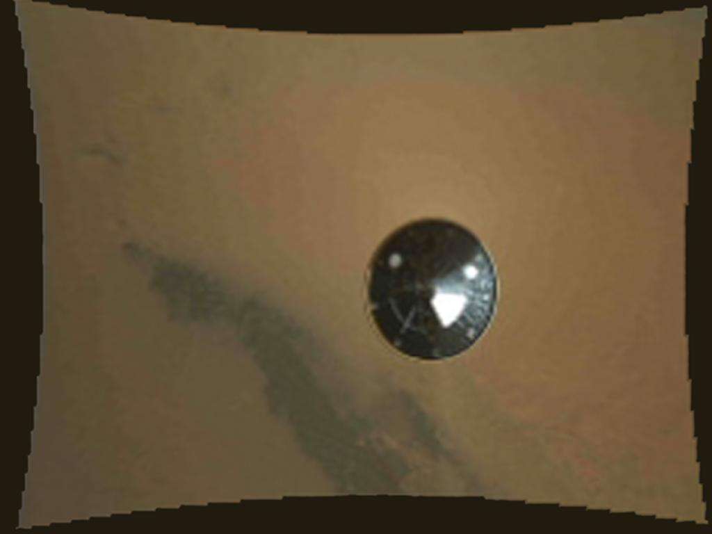 Le bouclier thermique tombe : il vient d'être largué, alors que le rover Curiosity et la grue aéroportée sont suspendus au grand parachute. La caméra Mardi (Mars Descent Imager) vient de commencer à filmer. Il reste moins de 3 minutes avant l'immobilisation au fond du cratère Gale. © Nasa, JPL-Caltech, MSSS