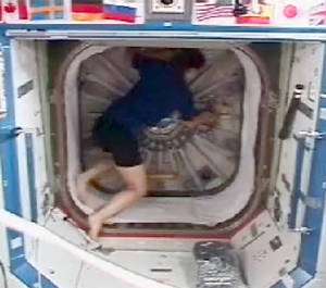 Peggy Whitson, commandante de la mission STS-122, en train d’ouvrir la porte circulaire entre le nœud de jonction Harmony et le laboratoire américain Destiny. © Nasa TV