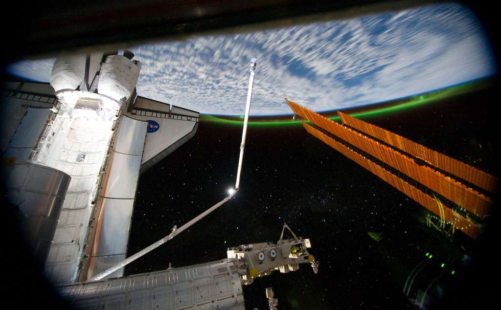 La navette Atlantis prise depuis l’ISS, avec la Terre en arrière-plan La navette Atlantis prise depuis l’ISS, avec la Terre en arrière-plan