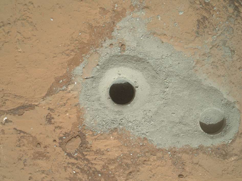 Après un premier forage d'essai (à droite), Curiosity, au « Sol » 182 (c'est-à-dire le 182e jour martien de sa mission), a percé un trou profond d'un peu plus de six centimètres. La poussière ainsi récupérée sera analysée à l'intérieur du rover d'ici quelques jours, le temps que la Nasa s'assure que les instruments n'ont pas été contaminés lorsqu'ils étaient sur Terre. © Nasa, JPL-Caltech, MSSS