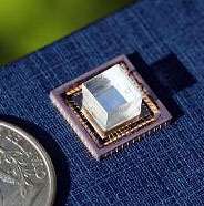 Figure 1. L'instrument, constitué d'un circuit et surmonté d'un cube transparent transmettant la lumière. A gauche, la pièce de monnaie, un quarter mesurant 24,26 millimètres de diamètre, donne l'échelle. © National Academy of Sciences, Pnas (2008) Figure 1. L'instrument, constitué d'un circuit et surmonté d'un cube transparent transmettant la lumière. A gauche, la pièce de monnaie, un quarter mesurant 24,26 millimètres de diamètre, donne l'échelle. © National Academy of Sciences, Pnas (2008)