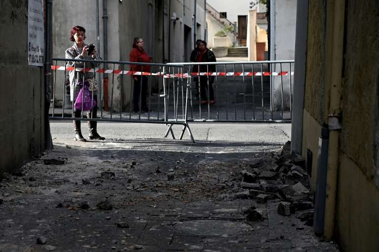 Une femme photographie des briques tombées d'un mur au Teil (Ardèche), le 11 novembre 2019, après un séisme de magnitude 5,4 dans la région. © Jeff Pachoud, AFP