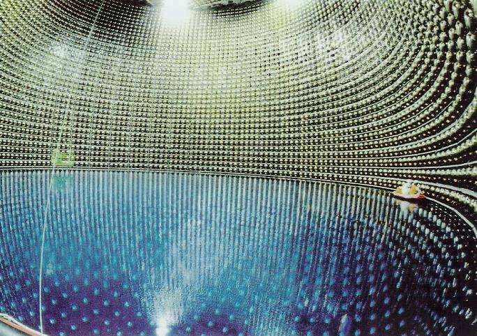 Le détecteur à neutrinos Kamiokande, vu lors de son remplissage. Les murs sont tapissés de photodétecteurs, dont on voit le nettoyage par l'équipe en bateau...