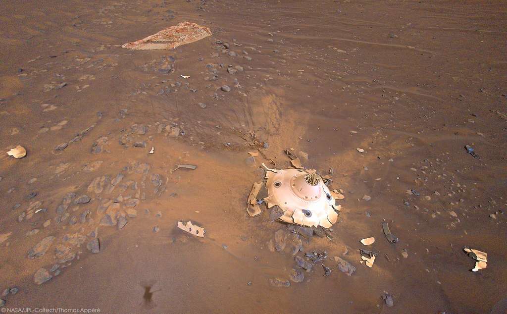 Magnifique prise de vue par le drone Ingenuity de la coque arrière de la capsule de descente de Perseverance, derrière se trouve le parachute. Les débris autour viennent de la capsule et témoignent de la violence de l'impact. En effet, après avoir largué l'étage de descente portant le rover, la coque s'est écrasée au sol à la vitesse de 126 km/h ! © Nasa, JPL-CalTech, Thomas Appéré