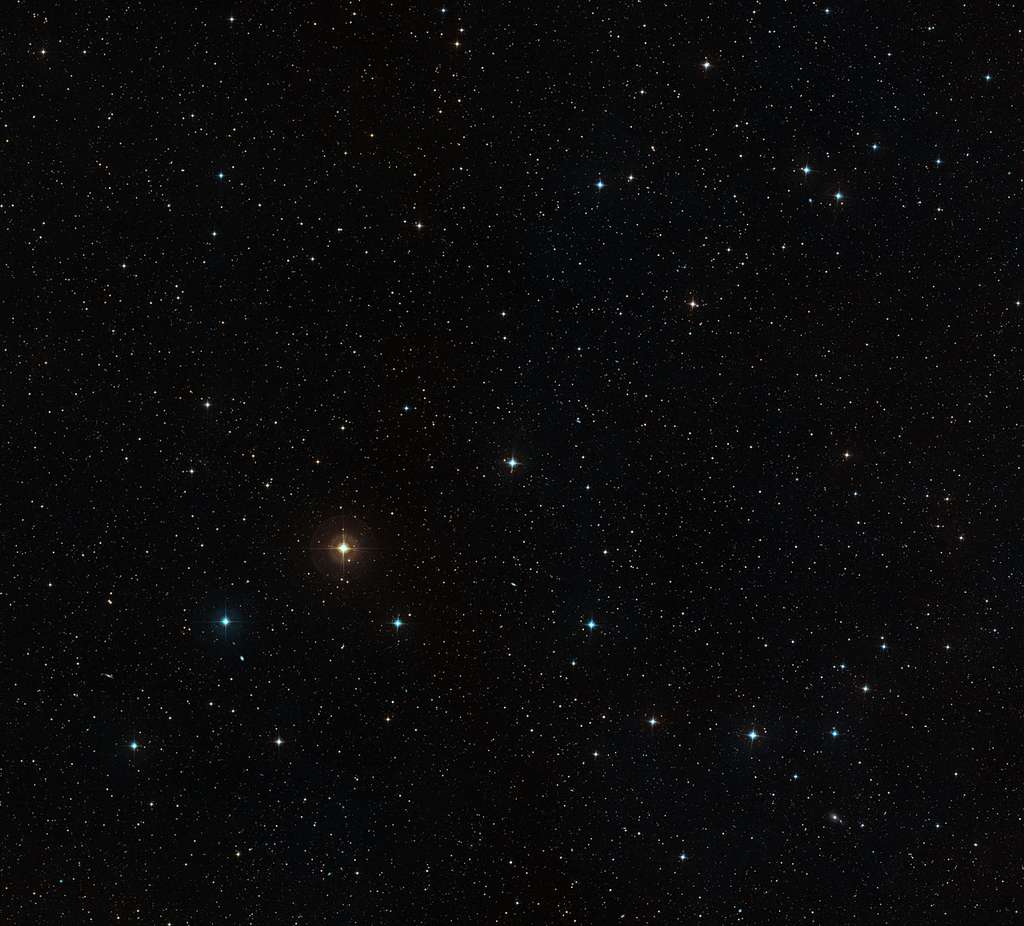 Cette image à grand champ montre le ciel autour de l'étoile HD 10180, qui apparaît comme une étoile assez brillante juste au-dessous du centre. L'image a été créée à partir de photographies prises avec des filtres rouge et bleu. Les halos colorés autour des étoiles sont des artefacts dus au procédé photographique. Crédit : ESO, Digitized Sky Survey 2/Davide De Martin.