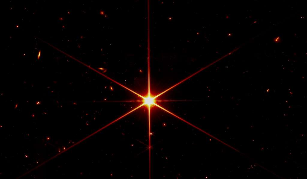 Cette image en fausse couleur de l'étoile, appelée 2MASS J17554042+6551277, utilise un filtre rouge pour optimiser le contraste visuel. C'est la première image unique d'une étoile obtenue avec le télescope spatial James-Webb. On voit d'autres étoiles et aussi des galaxies en arrière-plan. © Nasa, STScI