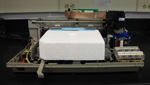 L'imprimante HP DeskJet 500 après les modifications. Elle peut désormais imprimer des cellules vivantes. Les fils orange (milieu et haut de la photo) sont utilisés pour court-circuiter le circuit d'alimentation de l'imprimante en papier. © Owczarczak et al. 2012, Jove