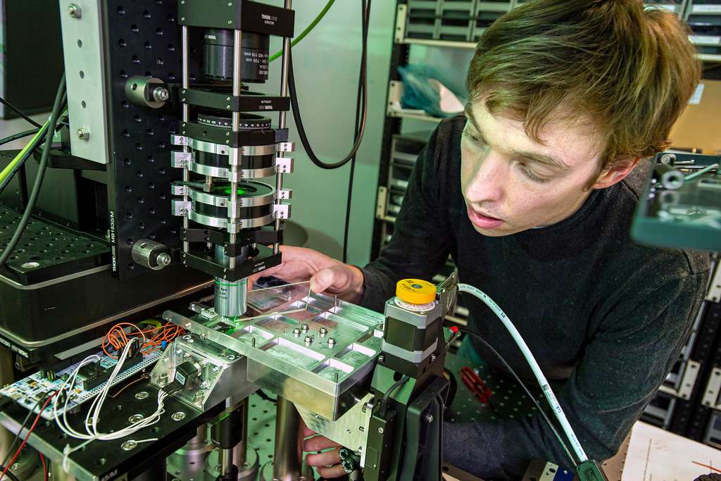 A Microsoft optical scientist is loading a piece of glass into a system using optics and artificial intelligence to extract and read data stored on glass.  © Jonathan Banks, Microsoft.