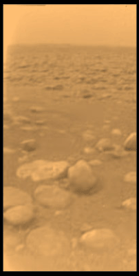 Photographie du sol de Titan, prise par Huygens en 2005. La sonde semble avoir atterri dans le lit asséché d’une ancienne rivière de méthane. Les pierres que l’on aperçoit sont en réalité de la glace d’eau. L’image a été colorisée pour recréer les véritables couleurs de Titan. © Nasa, JPL, ESA