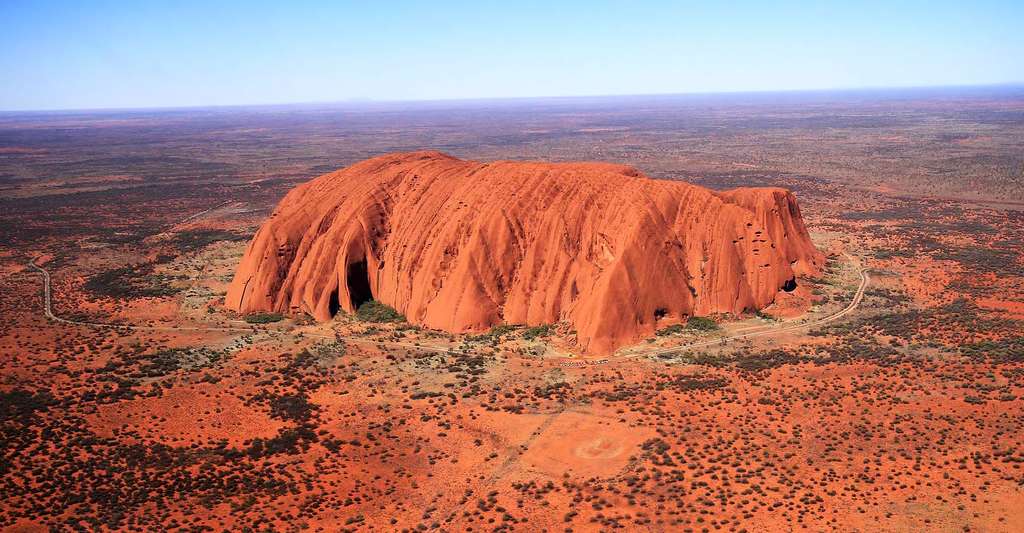 Uluru, aussi connu sous le nom anglais d’Ayers Rock, est un inselberg en grès au centre de l’Australie. C’est un lieu sacré pour les peuples aborigènes Pitjantjatjara et Yankunytjatjara. © Wales Jacqueline, domaine public