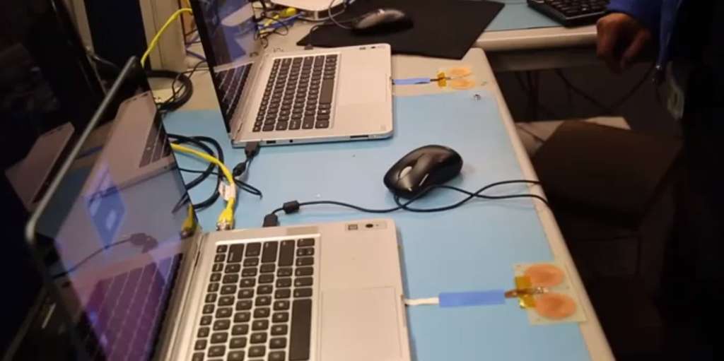 Deux étudiants stagiaires chez Intel ont mis au point un système de transfert de données via les ondes électromagnétiques du corps à l’aide d’une bague et de capteurs tactiles placés sur deux PC portables. On voit ici le prototype, sur cette image tirée d'une vidéo : les ordinateurs sont équipés de petites antennes plates capables de lire et d'écrire sur la mémoire incluse dans la bague portée au doigt et posée dessus. © Intel