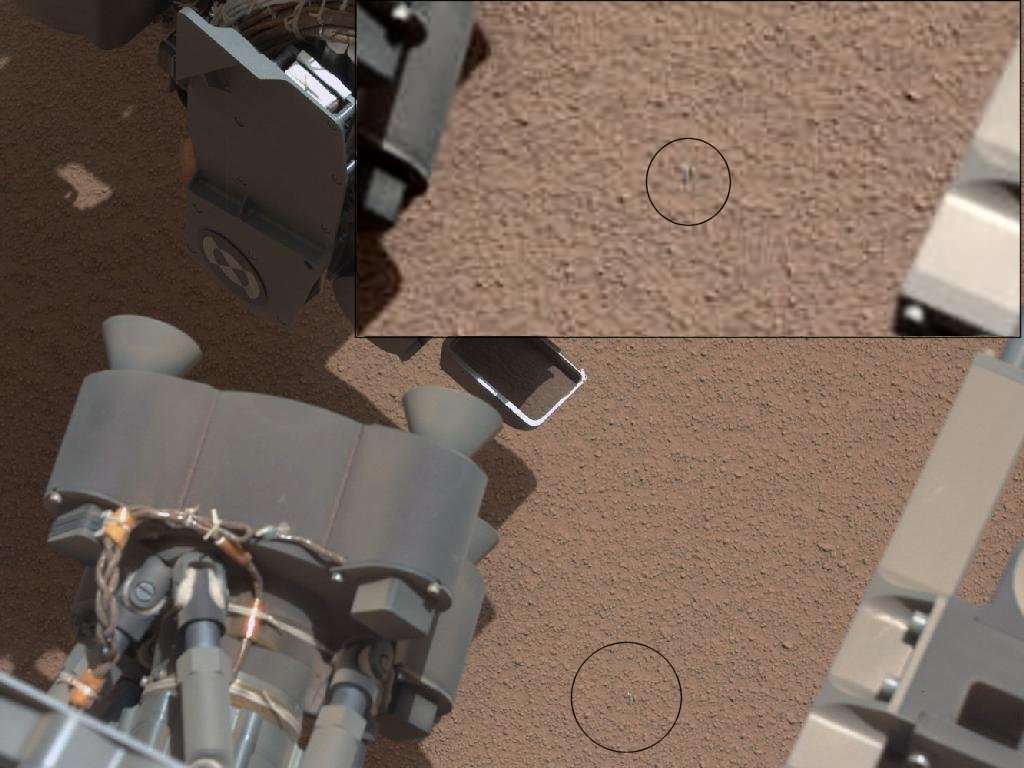 Les scientifiques de la mission MSL ont l'œil : sur une image prise par la caméra Mastcam, avec l'objectif à longue focale, ils ont repéré une petite chose grise (dans le cercle noir, en bas), dont l'agrandissement (en haut) montre qu'elle est très probablement artificielle et donc d'origine humaine... © Nasa/JPL-Caltech/MSSS - Montage : Futura-Sciences