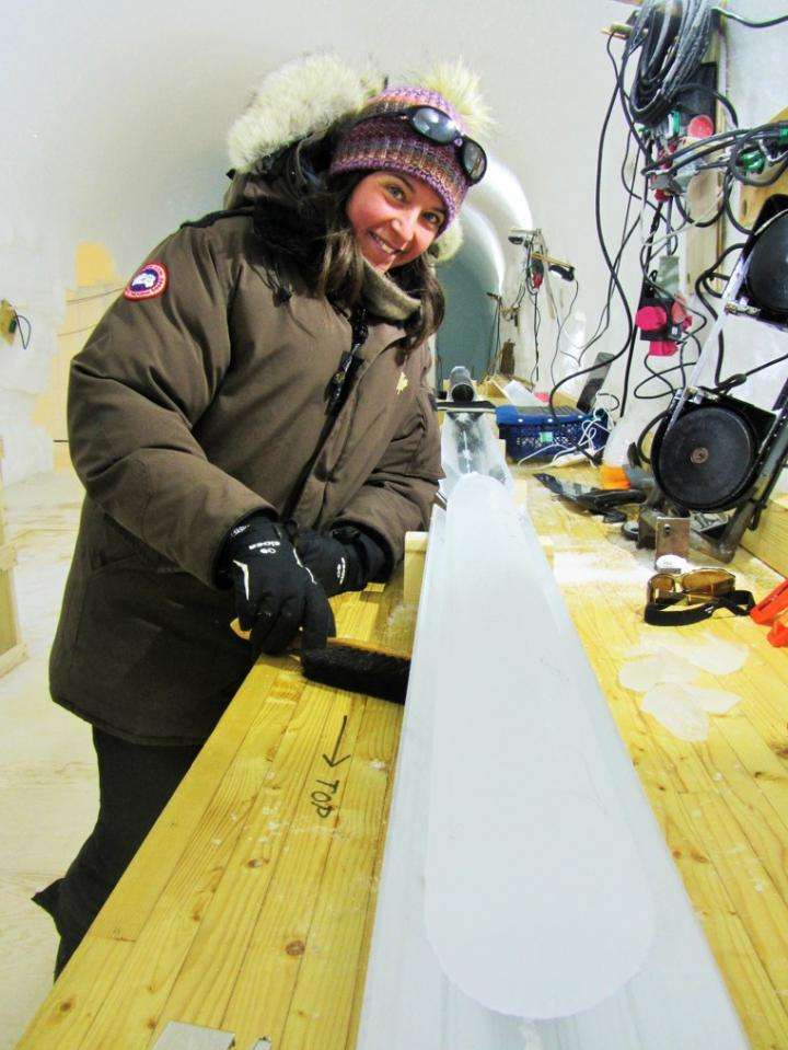 Emilie Capron se tient à côté d'une des carottes de glace utilisée dans cette étude. Cette carotte contient les précipitations déposées sur la calotte glaciaire du Groenland, durant plus de 100.000 ans. © Mari Jensen