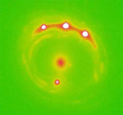 Sur cette image en fausses couleurs, obtenue en lumière visible mais amplifiée par une lentille gravitationnelle, on voit quatre points rouges correspondant au Quasar RXJ1131-1231. Au centre, il s'agit de la galaxie responsable de l'effet de lentille gravitationnelle. Crédits : Ohio State University