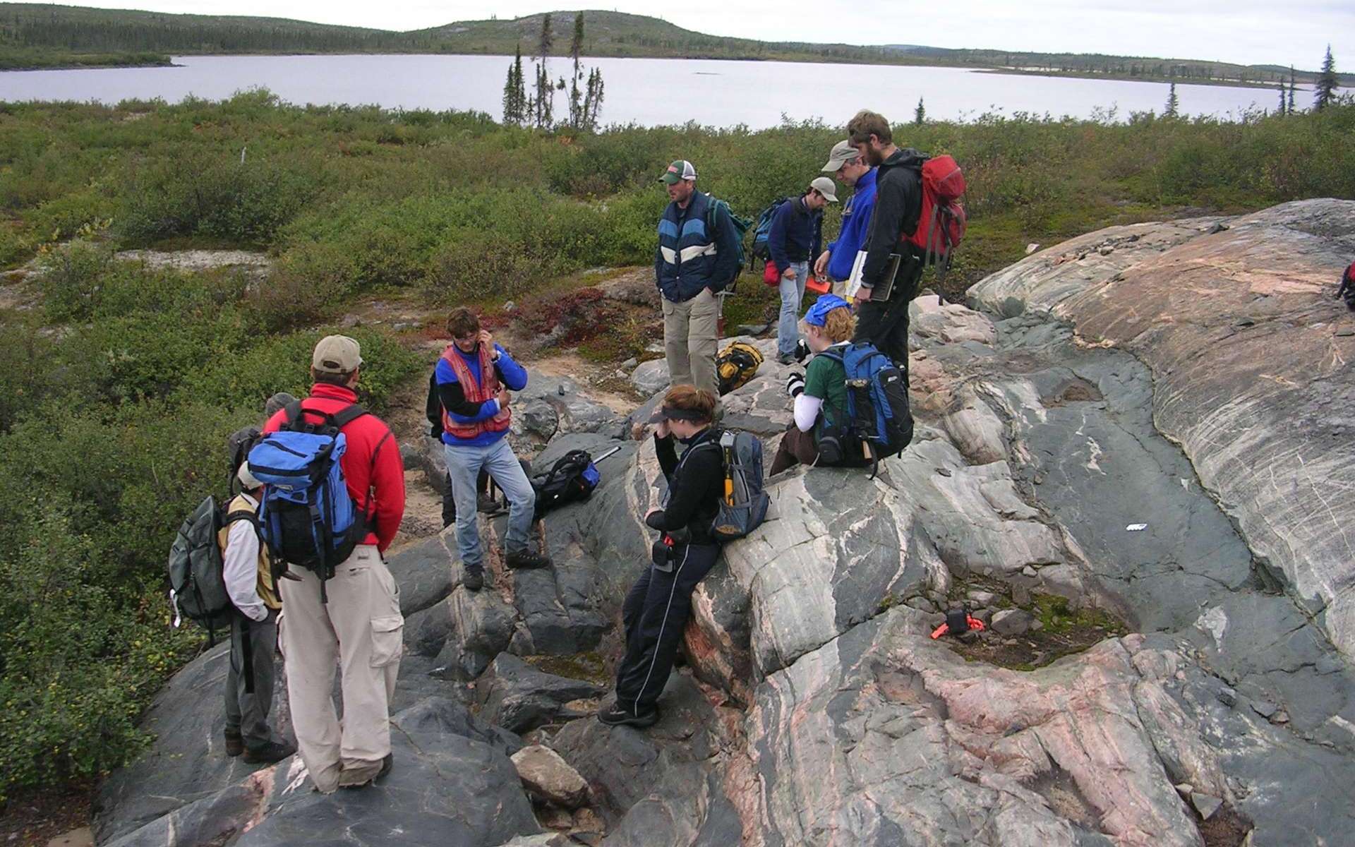 Une équipe d'étudiants en géologie examine l'affleurement rocheux de gneiss d'Acasta situé sur une île au Canada. Découvert en 1989, il tire son nom de sa proximité avec la rivière Acasta du Grand Lac de l'Ours. Ses roches ont des âges compris entre 4 à 3,58 milliards d'années et elles sont des vestiges de croûte continentale les plus anciens connus à ce jour. © Northwest Territories Geoscience Office