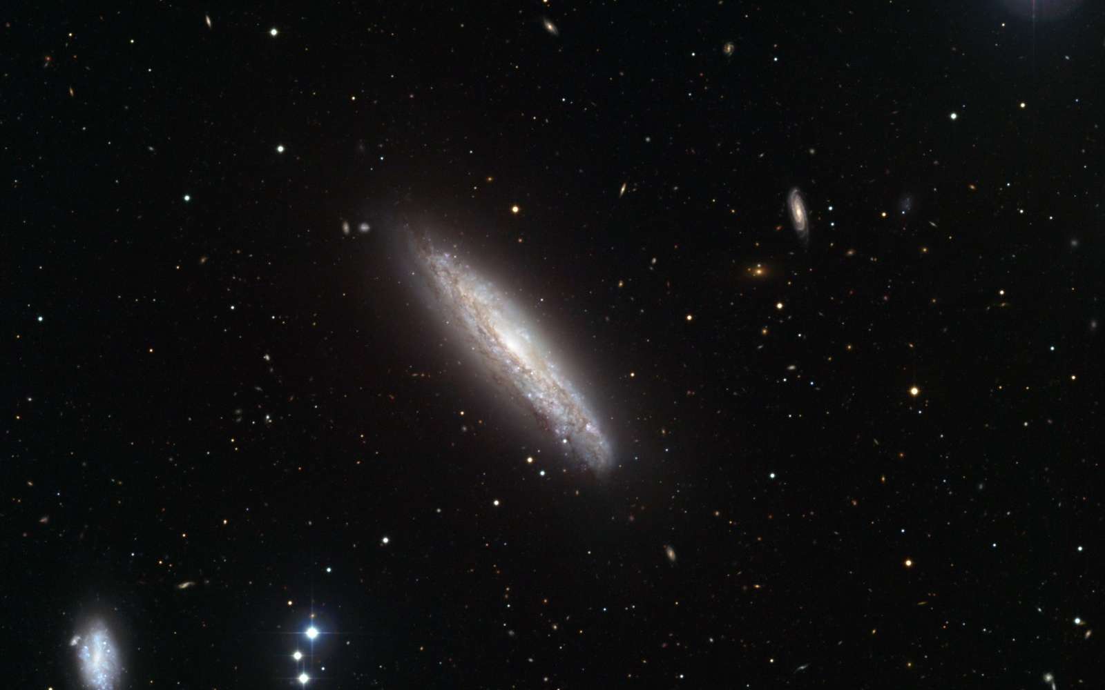 Tout autour de NGC 4666, d'autres galaxies (révélées sur cette image prise par l'un des télescopes de l'Eso) contribuent à une intense production d'étoiles ainsi qu'à la naissance d'un super-vent stellaire visible dans le rayonnement X. Crédit Eso/J. Dietrich