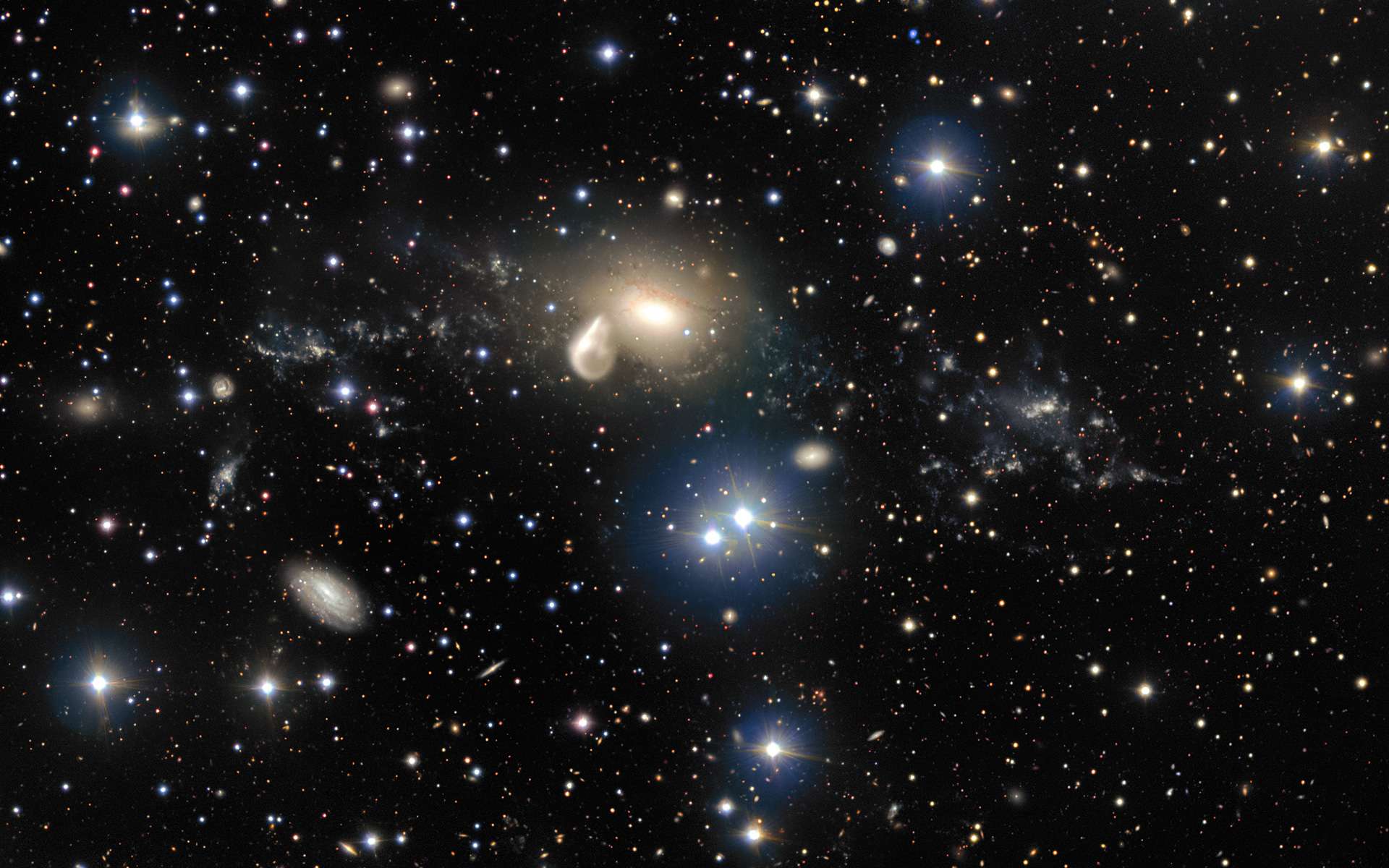 Cette image, acquise par le Très Grand Télescope (VLT) de l'Eso, à l'Observatoire du Cerro Paranal (Chili), révèle en détail les spectaculaires conséquences d'une collision cosmique vieille de 360 millions d'années. Parmi les débris qui entourent la galaxie elliptique NGC 5291 (au centre de l'image) figure un objet rare et mystérieux à la fois : une jeune galaxie naine (l'amas lumineux à droite). Cet objet offre aux astronomes l'excellente opportunité de mieux connaître ce type de galaxies, largement répandues dans l'univers jeune, mais généralement trop distantes et trop peu lumineuses pour pouvoir être observées au moyen des télescopes actuels. Ce spectacle pourrait prendre fin dans 2,8 milliards d'années avec un Big Rip. © Eso