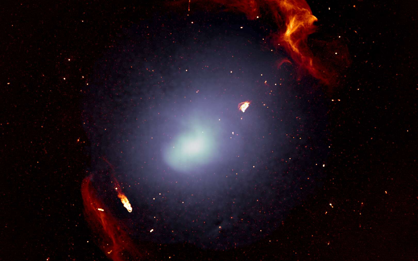 L'amas massif de galaxies Abell 3667 est observé dans le domaine radio, ce qui a permis de synthétiser cette image en fausses couleurs. Les galaxies individuelles sont trop petites pour être distinguées sur cette image. La couleur blanche montre la distribution du gaz qui imprègne l'espace au sein des galaxies de cet amas. Les structures rouges retracent les deux grandes ondes de choc générées lors de la formation de l'amas de galaxies. © Francesco de Gasperin, South African Radio Astronomy Observatory (Sarao)