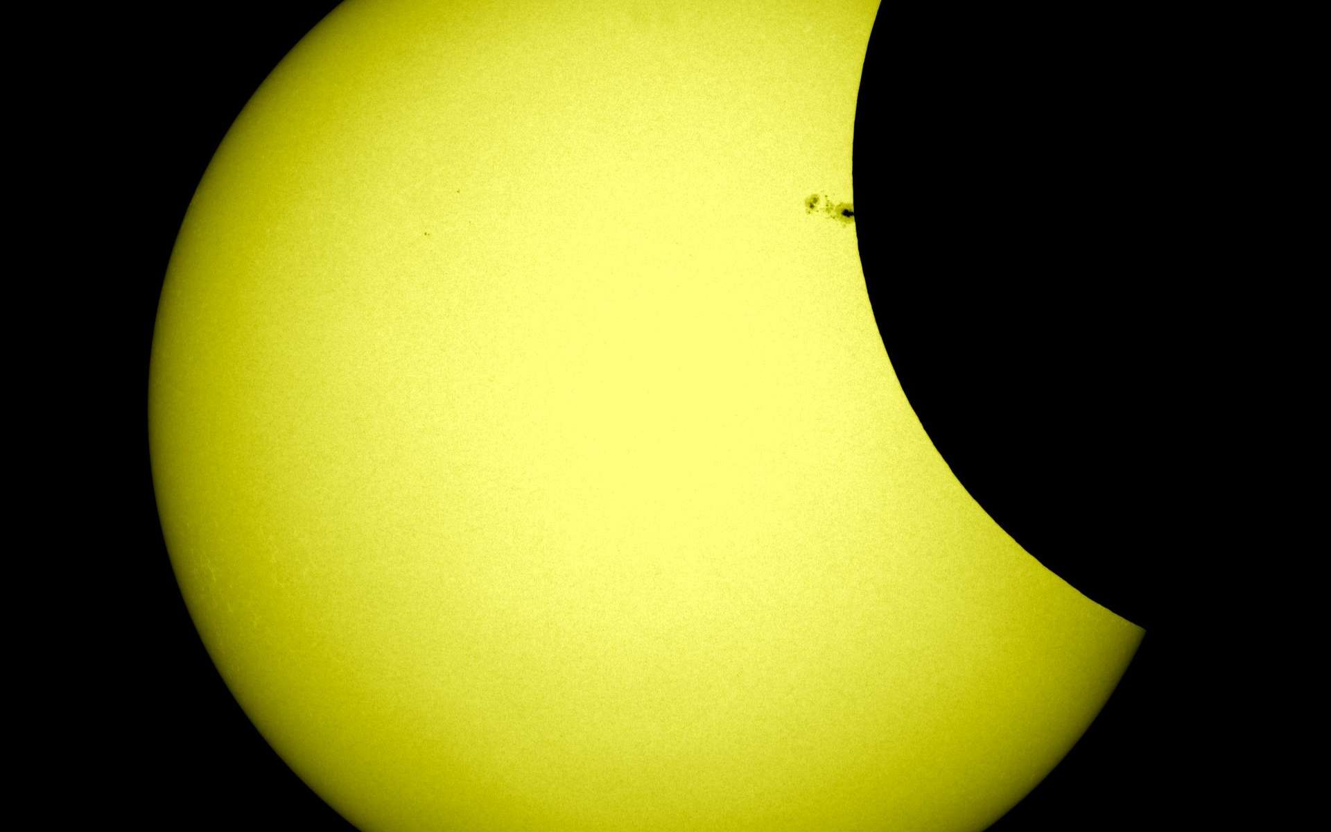 Pendant l'éclipse partielle du 21 février 2012, la Lune a brièvement masqué le groupe de taches solaires AR 1422, une occasion rare pour les scientifiques d'étudier la proportion des rayons UV émis par ces anomalies magnétiques. © Nasa/SDO