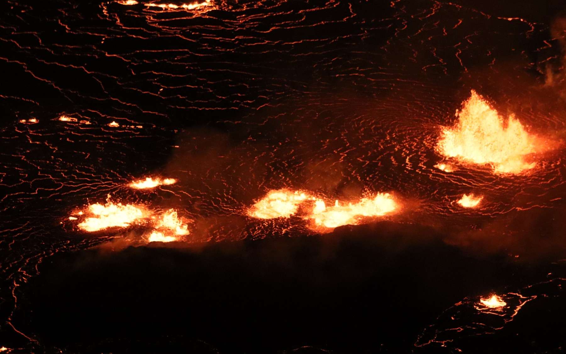 L'éruption en cours du sommet du Kīlauea dans le cratère Halema'uma'u continue d'alimenter les fontaines de lave basses au centre du lac de lave (photo) et le long du mur ouest du cratère Halema'uma'u. Cette image au téléobjectif regarde vers l'est au centre du lac de lave. La zone sombre sous les fontaines est « l'île de lave » qui s'est formée en décembre 2020. © USGS M. Patrick