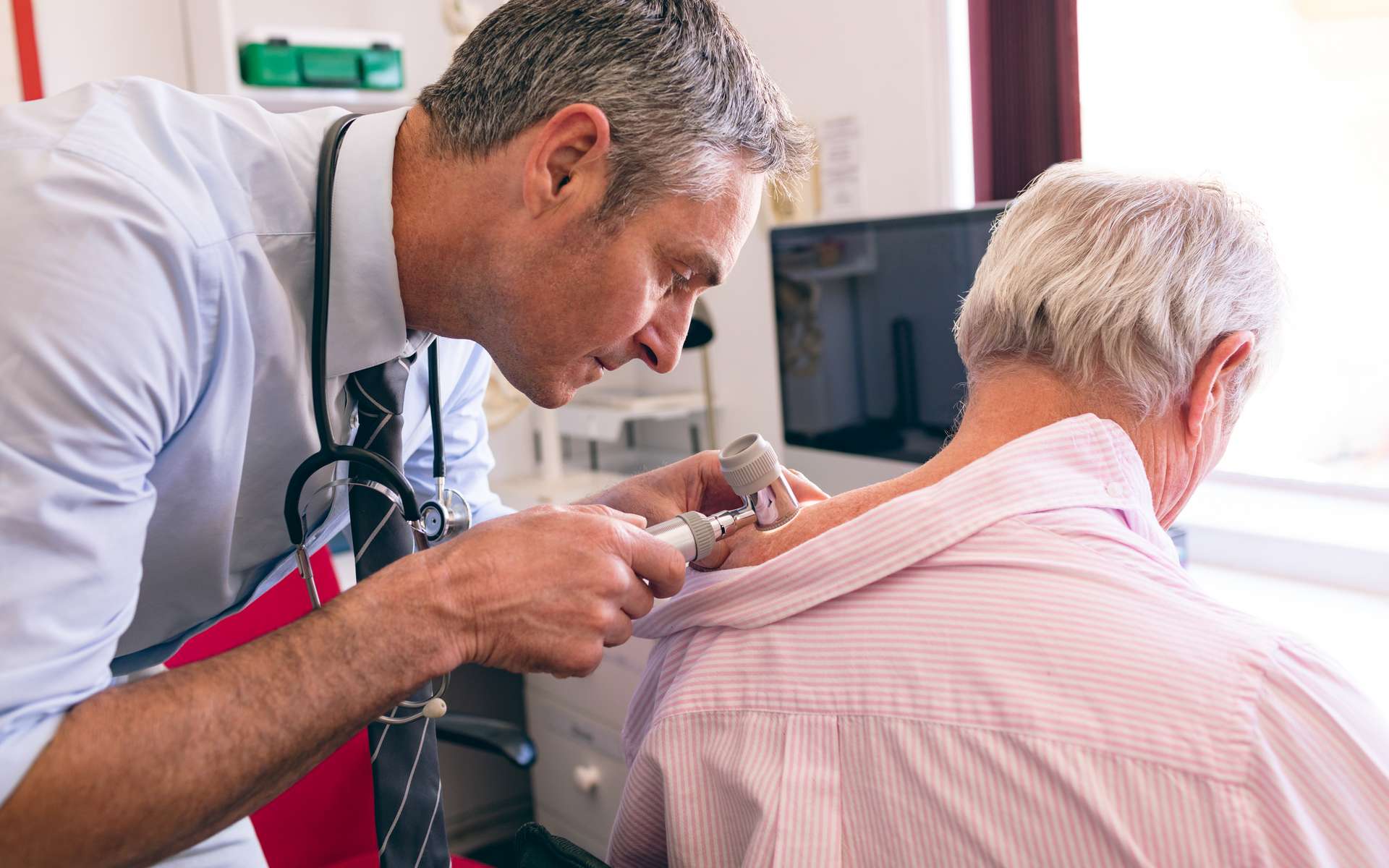 Un dermatologue vérifiant l'aspect d'une lésion cutanée chez une personne âgée. © Wavebreak 3, Adobe Stock