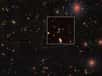 On relève parmi les 83 quasars nouvellement découverts, le troisième quasar le plus distant connu, dit HSC J1243+0100 (minuscule point rouge indiqué par une flèche), à une distance de 13,05 milliards d'années-lumière de nous, et aussi un des moins lumineux (publication de 2019). Il est vu ici par la caméra en lumière visible à grand champ Hyper Suprime-Cam (HSC) du télescope Subaru de l'Observatoire astronomique national du Japon (NAOJ). En son sein, se terre un trou noir de 300 millions de masses solaires. Des étoiles de la Voie lactée et d'autres galaxies figurent également sur l'image. © National Astronomical Observatory of Japan (NAOJ)