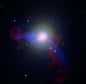 A 60 millions d’années-lumière de la Terre, la galaxie M87 est la plus grande de l’amas de la Vierge. De brillants jets visibles dans toutes les longueurs d’onde et qui se déplacent à une vitesse proche de la lumière s’échappent de son centre, qui abrite aussi un énorme trou noir. Associé avec le nuage de gaz chaud qui s’étend sur une grande partie de l’amas, celui-ci a été identifié comme une puissante source de rayons X et radio, Virgo A.