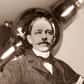 Ingénieur en électricité et inventeur américain, Peter Cooper Hewitt est né le 5 mai 1861 à New York. Fils du maire Abram Hewitt et petit-fils de l'industriel Peter Cooper, Hewitt bénéficie d'une éducation supérieure, à l'institut de technologie Stevens et à l'école des mines de l'université de Columbia.
Peter Cooper Hewitt invente la lampe à vapeur de mercure
Il invente la première lampe à vapeur de mercure en 1901, et la perfectionne en 1903 en améliorant les couleurs, qu'il arrive à rendre plus intenses. Cette nouvelle version rencontre un succès important par son usage industriel. La lampe à vapeur de mercure fonctionne sur le principe des lampes à décharge. Deux électrodes situées aux extrémités de la lampe créent une différence de potentiel qui ionise les molécules de mercure. Les électrons et les ions libérés traversent l'ampoule et émettent des photons qui, lorsqu'ils s'entrechoquent, créent de la lumière. L'invention d'Hewitt est plus efficace que les lampes à incandescence, mais sa lumière bleu-vert limite son application à des domaines où la couleur n'est pas problématique, comme la photographie.
Les autres inventions de Peter Hewitt
Peter Hewitt développe en 1902 la première diode à vapeur de mercure qui permet de transformer le courant alternatif en un courant continu. L'invention sera notamment utilisée dans les chemins de fer électriques, l'industrie, et le courant continu à haut-voltage. Il met au point et teste en 1907 un prototype d'hydroptère, un bateau dont la coque peut se détacher de la surface de l'eau. En 1916, associé à Elmer Sperry, Hewitt participe à l'élaboration de l'avion automatique Hewitt-Sperry, précurseur des missiles de croisières.
Marié à Lucy Bond Work, il est le beau frère de l'arrière-grand mère de la princesse de Galles, Diana. Peter Hewitt meurt le 25 août 1921.