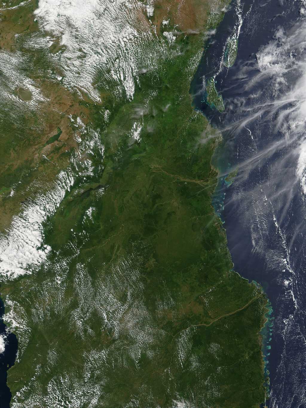 En haut à gauche de cette photo de la Tanzanie, la plaine du Serengeti se dresse derrière les nuages. En bas à gauche, le lac Malawi traverse la Tanzanie au nord jusqu'au Mozambique au sud. De nombreuses traînées d'avions dessinent des lignes blanches au dessus de l'océan Indien, à droite de l'image. © Nasa, 2002