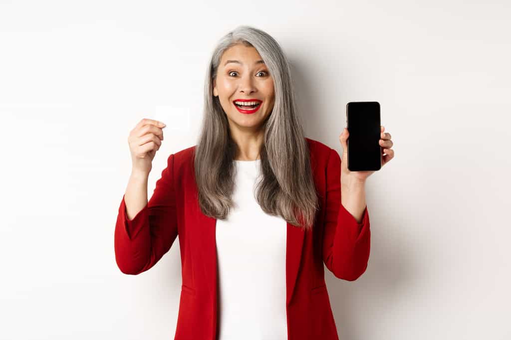 Une femme senior utilise son smartphone en toute simplicité : avec les forfaits mobiles adaptés