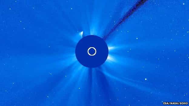 Dans la nuit du 28 au 29 novembre, l'observatoire solaire Soho repérait un éclat, que l'on voit ici en haut à gauche du disque masquant le Soleil. La trajectoire de la comète Ison vient d'en bas à droite sur cette image. Débris de queue voué à disparaître, ou fragment survivant du noyau ? On l'ignore encore, mais il est certain que la comète s'est en partie disloquée. © Nasa