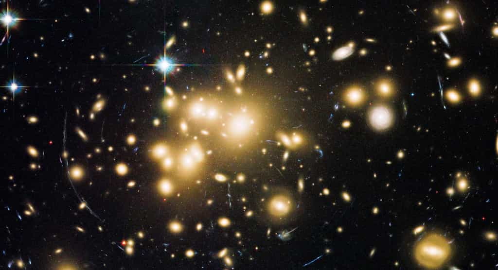 La présence de la matière noire dans les amas galactiques peut être déduite de l'effet de lentille gravitationnelle forte qu'elle génère, comme sur cette image prise par Hubble de l'amas Abell 1689 montrant des arcs lumineux. Il se pourrait que la lumière soit déviée, ironiquement, parce que l'amas contient des photons noirs. © Nasa