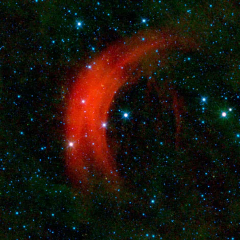 Alpha Camelopardalis, brillante étoile au centre de l'image, se déplace très vite dans l'espace et repousse la matière interstellaire sous la forme d'un voile rouge. © Nasa/JPL-Caltech/ Wise Team