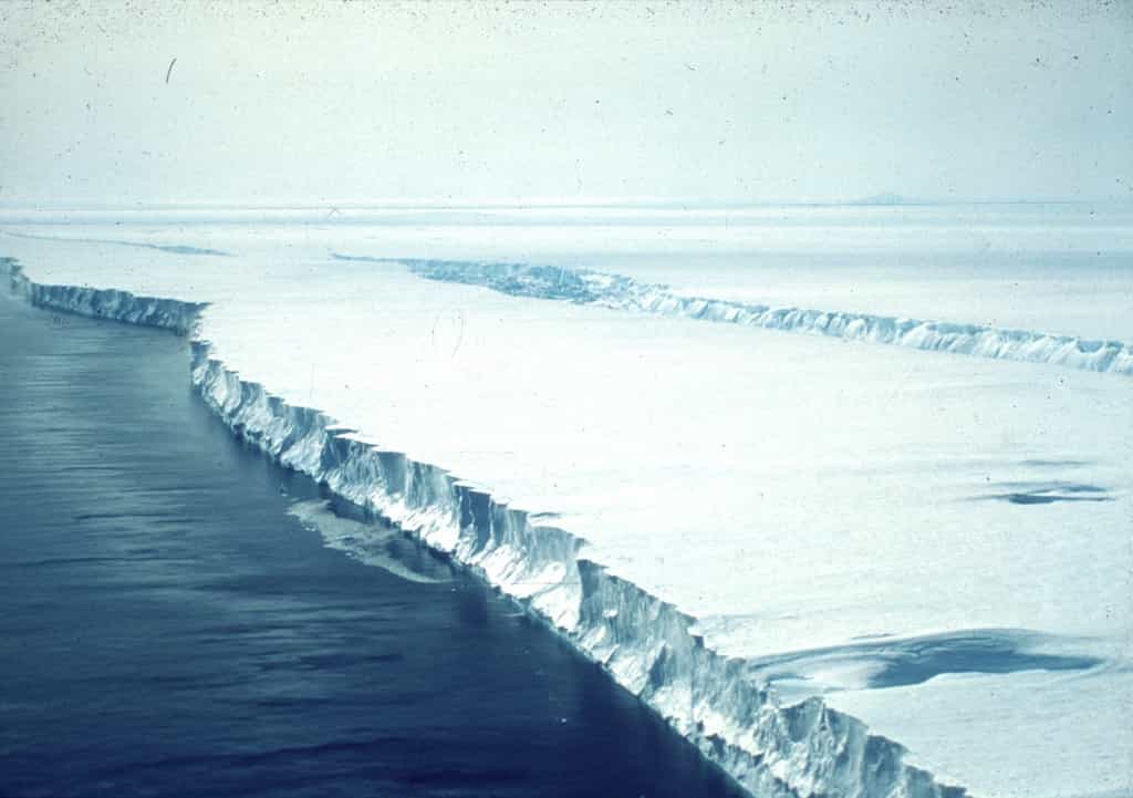 Dislocation d'une plateforme glaciaire en Antarctique. De telles couches de glace flottent sur l'océan au débouché de grands glaciers et en réduisent la vitesse d'écoulement. Quand une telle plateforme se disloque, le glacier qu'elle freinait s'écoule plus rapidement et le front de glace se brise plus facilement, libérant de nombreux icebergs. © Scott Polar Research Institute