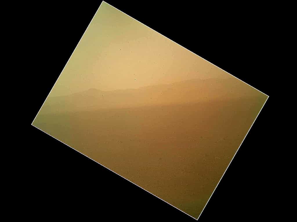 La photo ratée... Prise quelques heures après l'atterrissage par la caméra Mahli (Mars Hand Lens Imager), elle montre les parois, lointaines, du cratère Gale. Cet instrument est porté par le bras articulé, toujours en position repliée. Le flou de l'image vient de la poussière. Non, Curiosity ne s'est pas posé au milieu d'une tempête de sable. Cette poussière est celle qui s'est déposée sur le cache de l'objectif, toujours en place. Ce n'est pas un oubli, bien sûr. Transparent, il protège la caméra et permet, même fermé, ce genre de prise de vue. Quand Curiosity commencera à travailler et qu'il dépliera son bras, portant plusieurs instruments, ce cache sera retiré. © Nasa, JPL-Caltech, Malin Space Science Systems