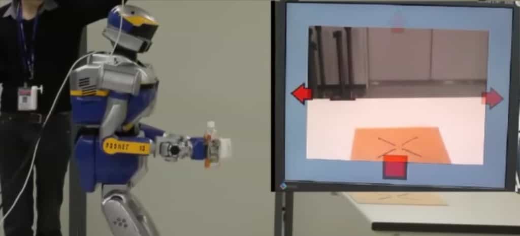 Les chercheurs français et japonais du Joint Robotics Laboratory  sont parvenus à développer un système de contrôle par la pensée  multitâche grâce auquel il est possible de réaliser plusieurs actions.  Ici, le robot a saisi une bouteille et il est ensuite guidé vers une  table où il ira la déposer, le tout entièrement piloté à partir des  pensées émises par l’opérateur humain équipé d’un casque EEG. © CNRS-AIST JRL 